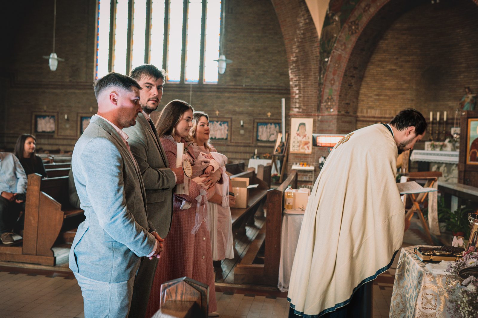 Priest and family during a baptism ceremony in church.