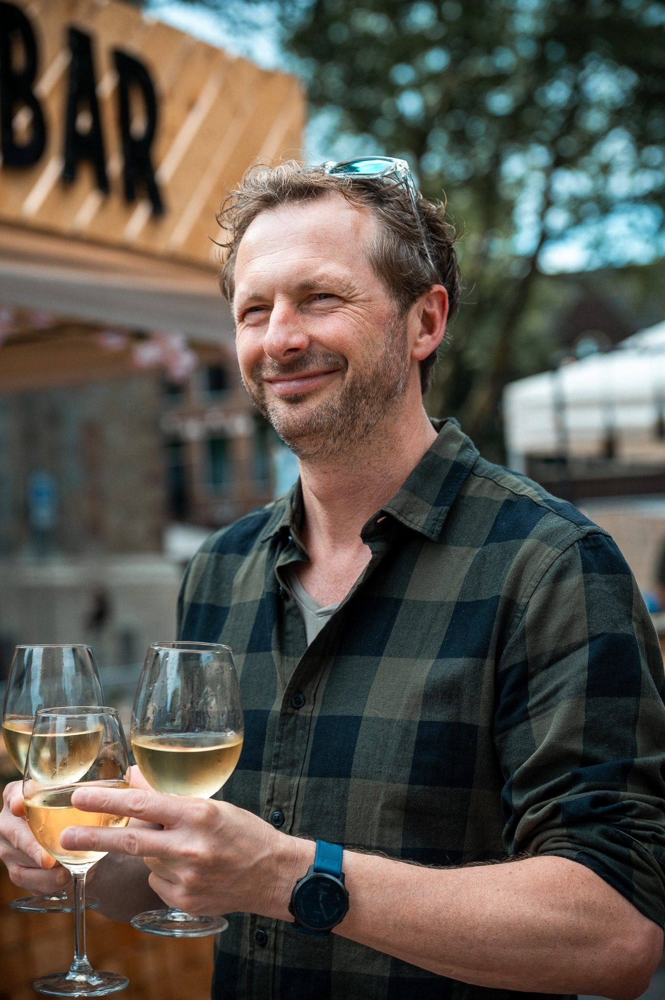 A guest holding wine glasses in a natural event portrait.