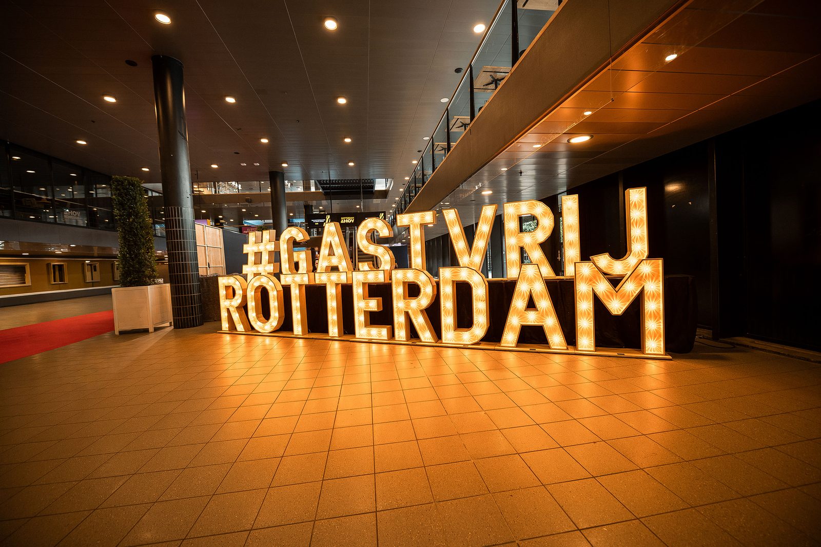 Illuminated Gastvrij Rotterdam sign at a hospitality trade event.