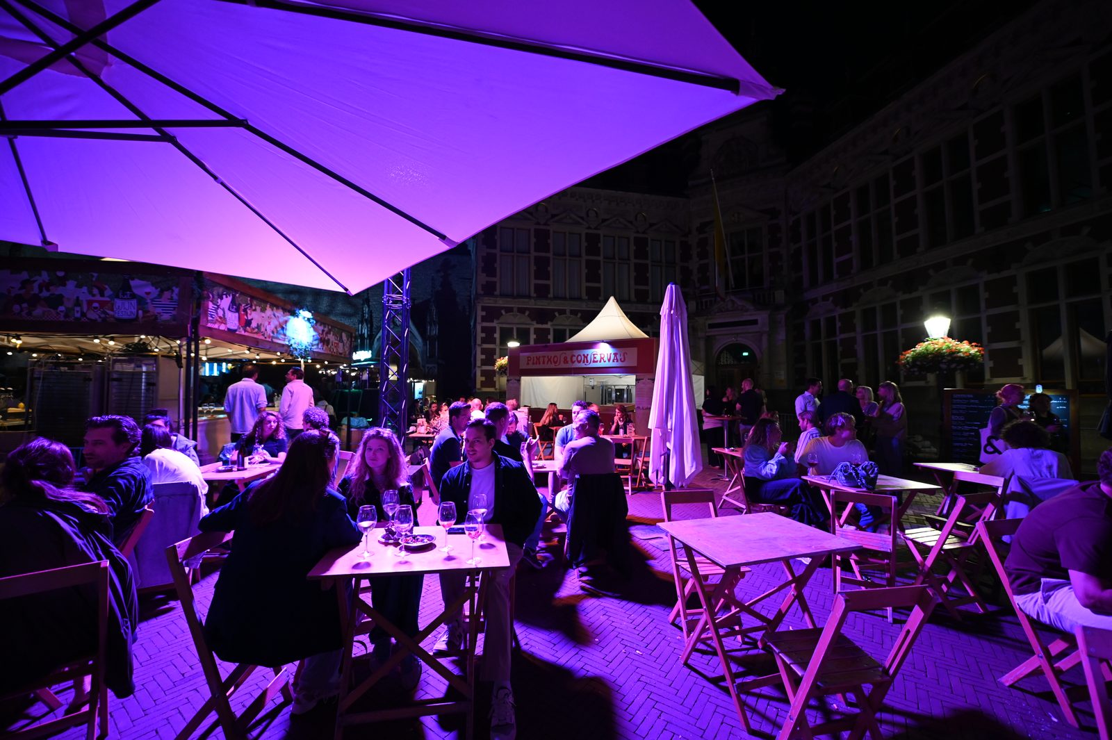 Wine festival tables lit with purple evening light in Utrecht.
