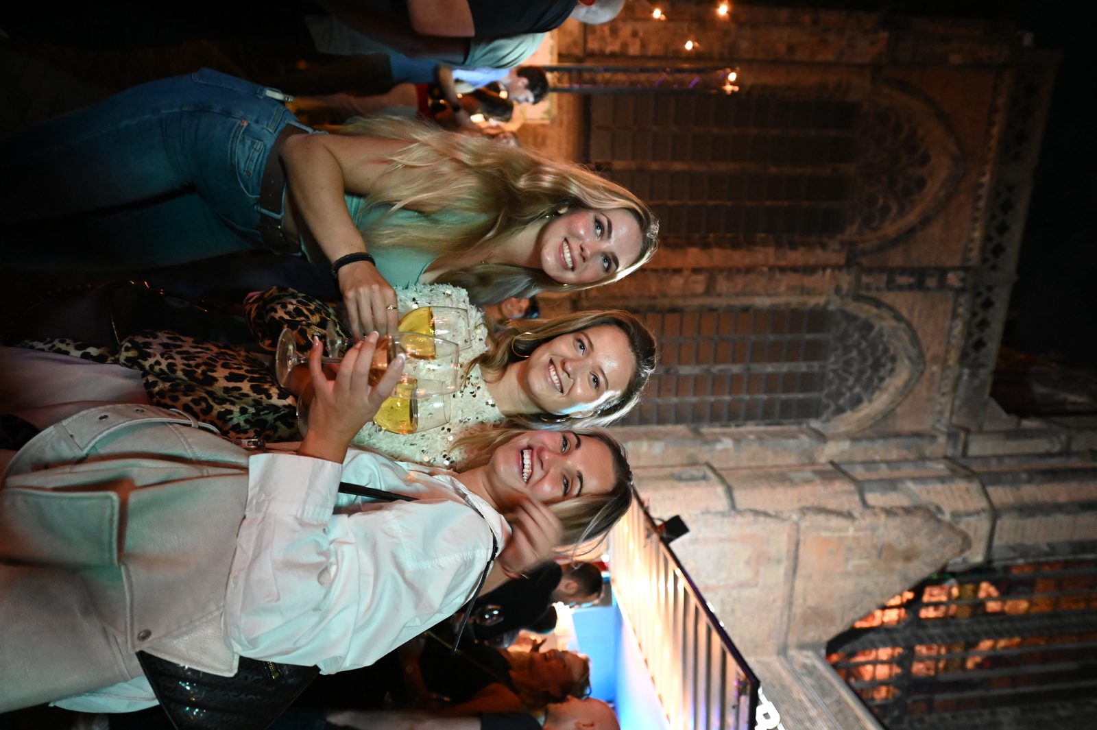 Three guests smiling with drinks at a wine festival in Utrecht.