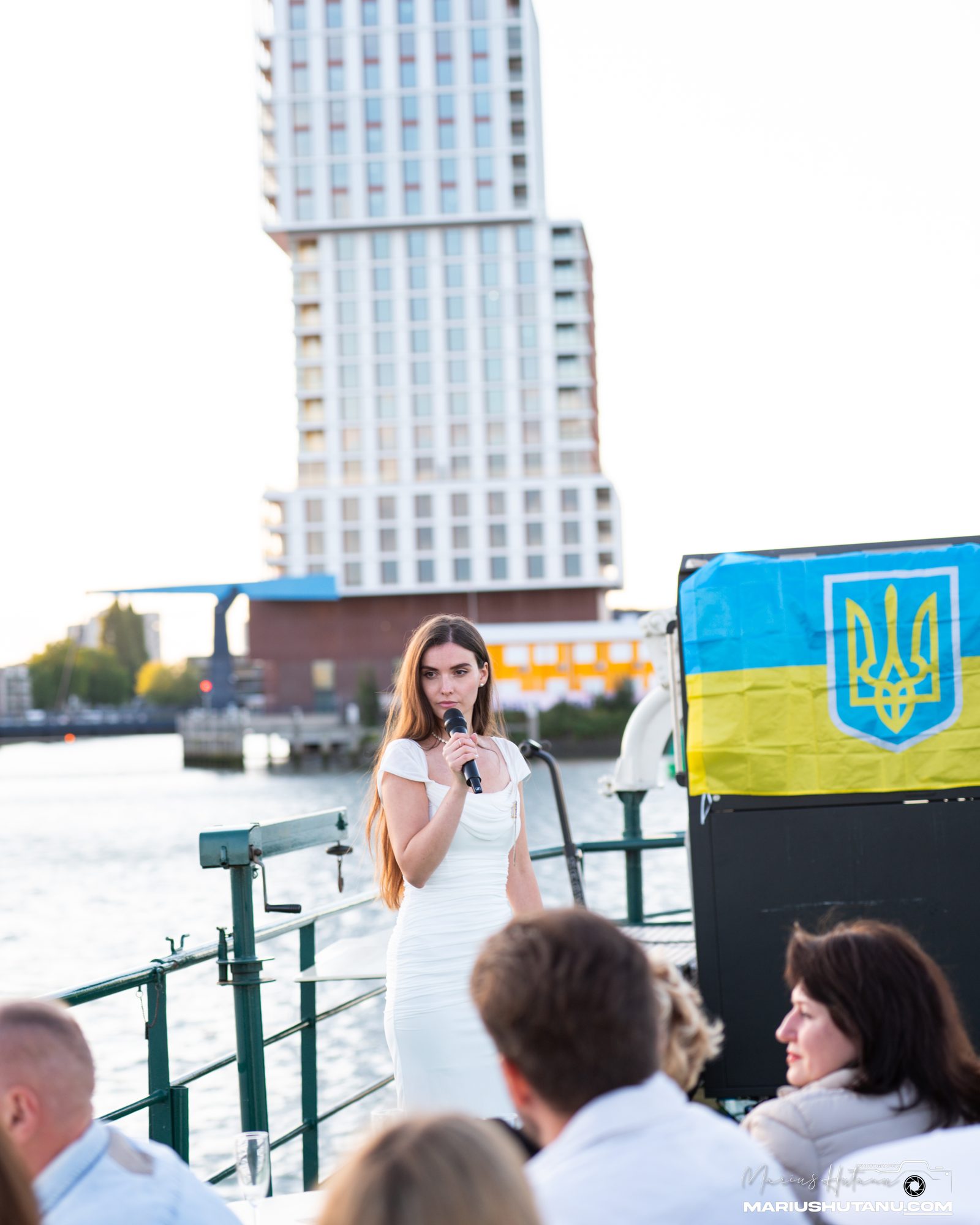 Host speaking into a microphone on a boat deck.